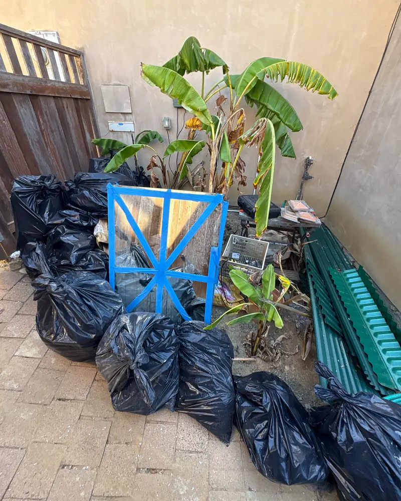Bagged yard waste and debris on a patio before haul-away